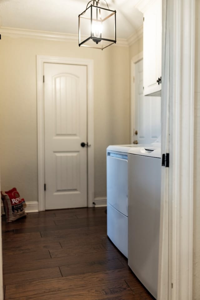 clothes washing area featuring washer and clothes dryer, dark wood-type flooring, ornamental molding, and cabinets