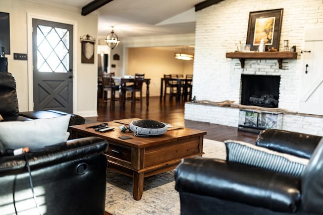 living room featuring hardwood / wood-style floors, a fireplace, lofted ceiling with beams, and a chandelier