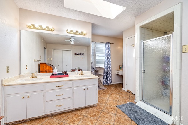 2029 China St, Brady, TX 76825 - bathroom featuring a stall shower, a skylight, double vanity, tile patterned floors, and a textured ceiling