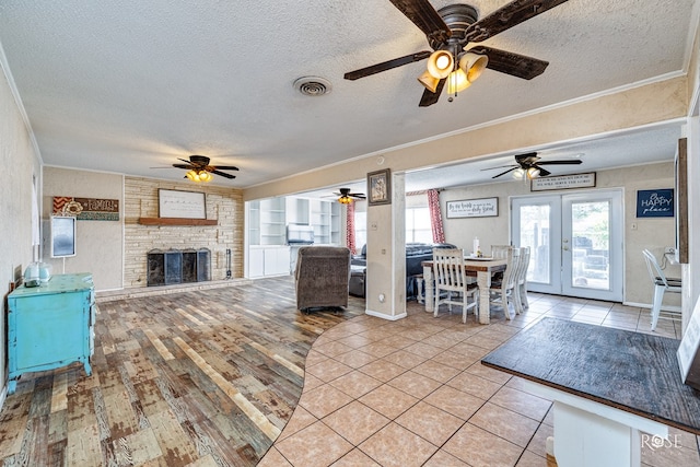 2029 China St, Brady, TX 76825 - living area featuring a textured ceiling, a ceiling fan, ornamental molding, a stone fireplace, and light wood-style floors