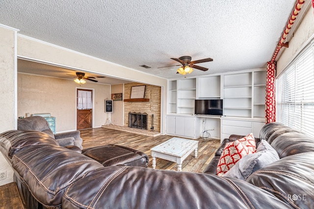 2029 China St, Brady, TX 76825 - living area with ceiling fan, a textured ceiling, wood-type flooring, and a fireplace