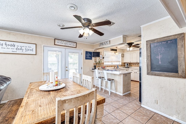 2029 China St, Brady, TX 76825 - dining room featuring a ceiling fan, a textured ceiling, crown molding, light tile patterned floors, and french doors