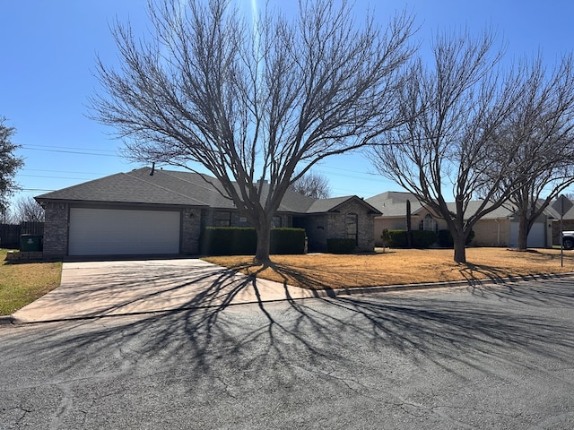 ranch-style home with an attached garage, driveway, roof with shingles, and brick siding