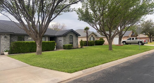 view of front of house with brick siding, a front lawn, an attached garage, and a shingled roof