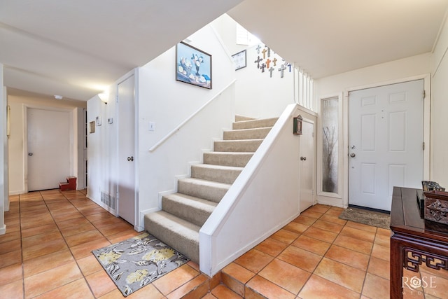 entrance foyer with light tile patterned floors, stairway, and visible vents