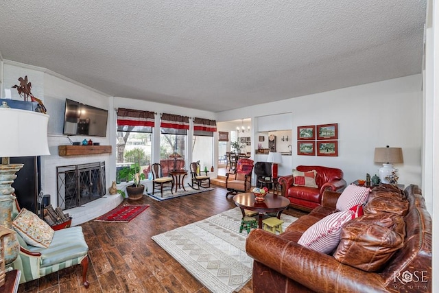 living area featuring a textured ceiling, wood finished floors, an inviting chandelier, and a fireplace with raised hearth