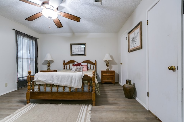 bedroom featuring a textured ceiling, dark hardwood / wood-style floors, and ceiling fan