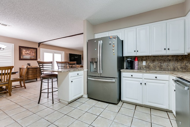 kitchen with a kitchen breakfast bar, kitchen peninsula, white cabinets, and appliances with stainless steel finishes