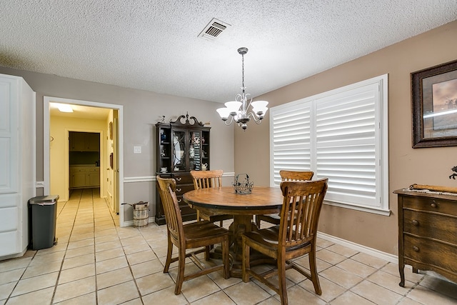 dining area featuring light tile patterned floors, a textured ceiling, and a chandelier