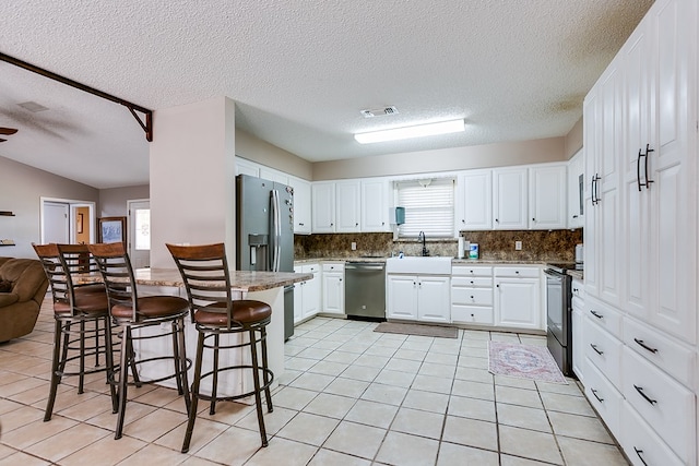 kitchen with sink, white cabinetry, tasteful backsplash, appliances with stainless steel finishes, and a kitchen breakfast bar