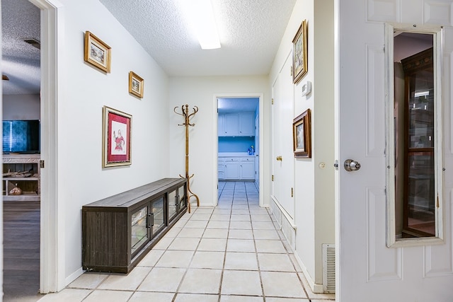 hall with light tile patterned floors and a textured ceiling