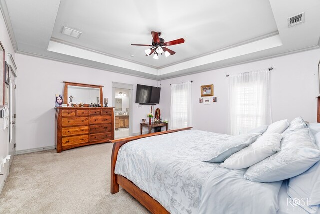 bedroom with light carpet, visible vents, and a tray ceiling