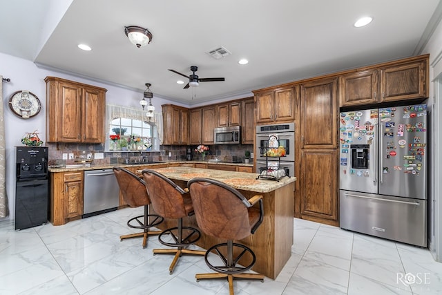 kitchen featuring a breakfast bar, light stone counters, tasteful backsplash, a center island, and stainless steel appliances