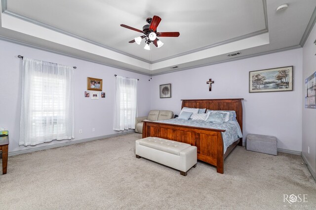 carpeted bedroom with baseboards, visible vents, a ceiling fan, a tray ceiling, and crown molding