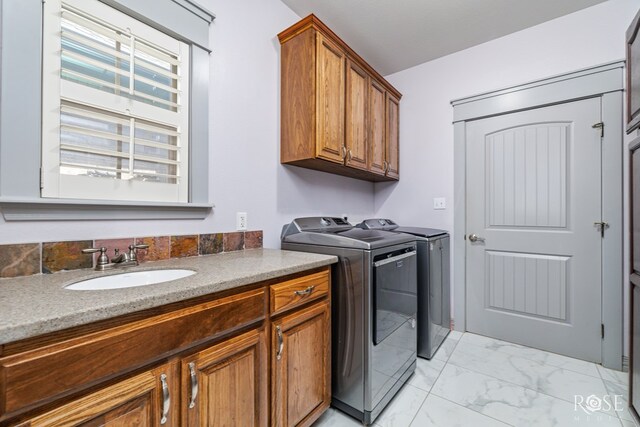 laundry room featuring marble finish floor, cabinet space, a sink, and washer and clothes dryer