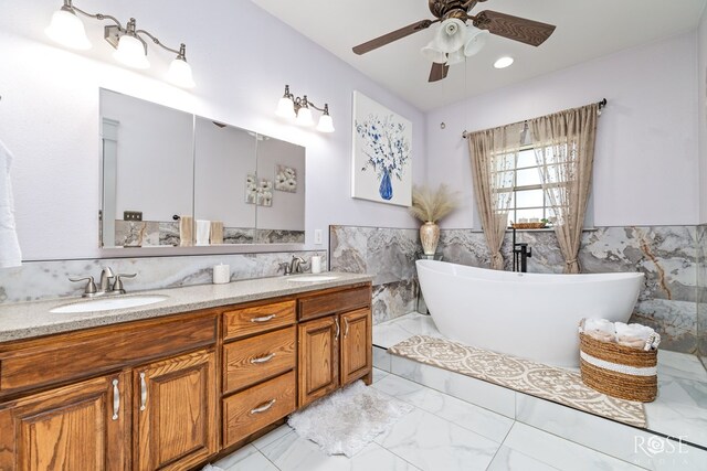 bathroom with a freestanding tub, marble finish floor, a sink, and double vanity