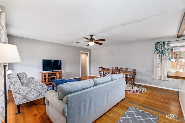 living area featuring ceiling fan, baseboards, and wood finished floors