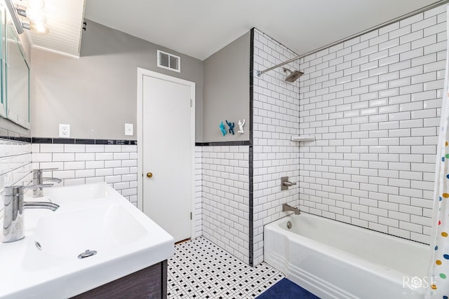 full bath featuring shower / bath combination with curtain, tile walls, visible vents, and a sink