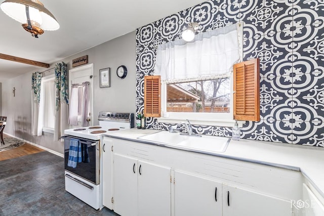 kitchen featuring white electric stove, light countertops, white cabinetry, a sink, and baseboards