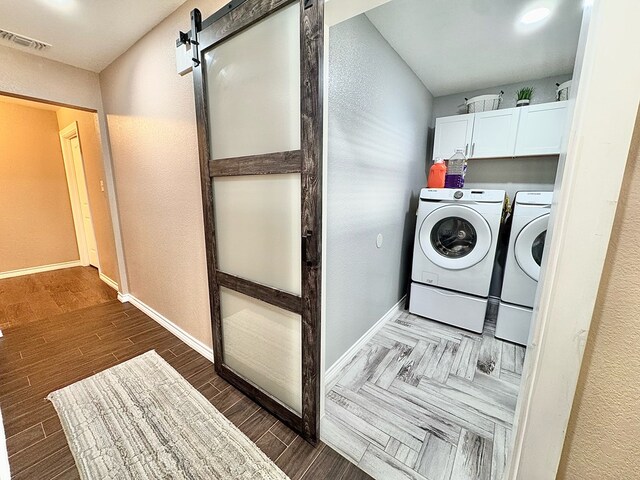 laundry area with cabinets, a barn door, and independent washer and dryer