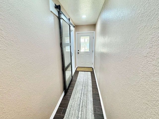 doorway with a barn door and a textured ceiling