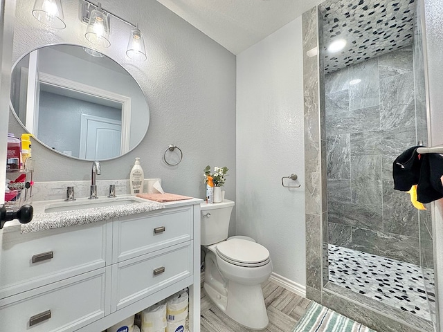 bathroom featuring vanity, a tile shower, and toilet