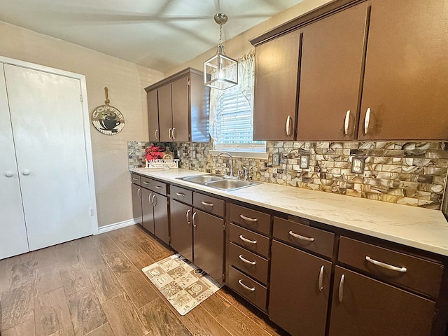 kitchen with sink, dark hardwood / wood-style floors, tasteful backsplash, dark brown cabinetry, and decorative light fixtures