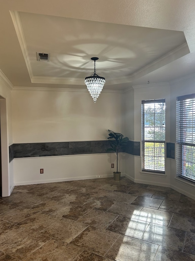 spare room with crown molding, a raised ceiling, and an inviting chandelier