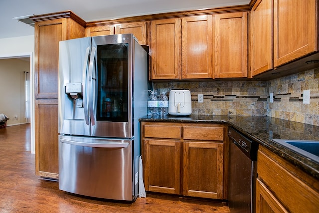 4974 Scarlet Oak Dr, San Angelo, TX 76904 - kitchen with appliances with stainless steel finishes, tasteful backsplash, dark wood-style floors, brown cabinets, and dark stone countertops