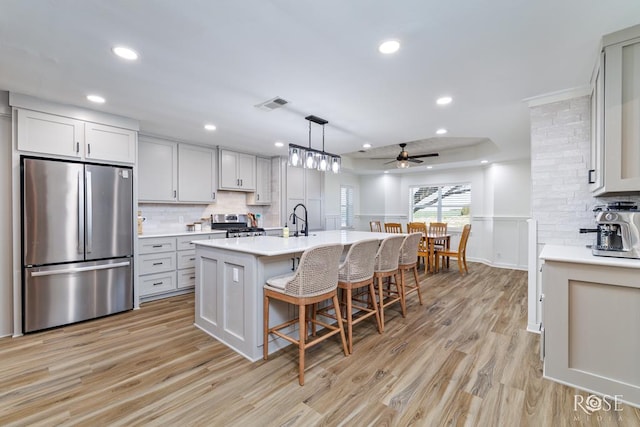 kitchen with a kitchen bar, visible vents, stainless steel appliances, light wood-style floors, and light countertops