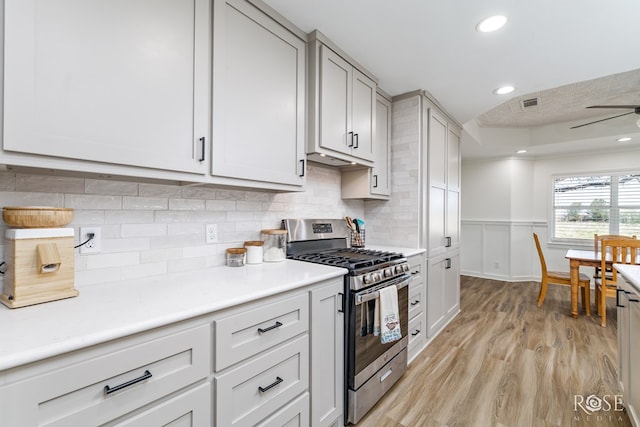 kitchen featuring a ceiling fan, visible vents, light wood finished floors, stainless steel range with gas stovetop, and light countertops