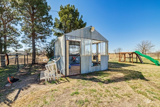 view of greenhouse with a playground, a yard, and fence