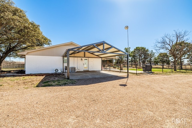 view of front of property with central air condition unit, driveway, a carport, fence, and brick siding