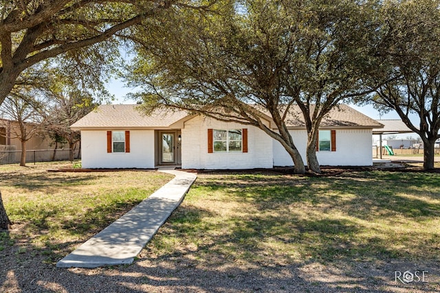 single story home with a front yard, fence, brick siding, and a shingled roof