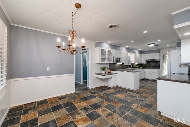 2305 Douglas Dr, San Angelo, TX 76904 - kitchen featuring stainless steel microwave, stone tile flooring, dark countertops, crown molding, and recessed lighting