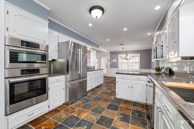 2305 Douglas Dr, San Angelo, TX 76904 - kitchen featuring stainless steel appliances, crown molding, a peninsula, stone tile flooring, and white cabinetry