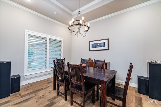 dining area with an inviting chandelier, hardwood / wood-style flooring, ornamental molding, and a raised ceiling