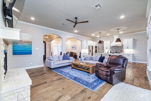 living room featuring ornamental molding, sink, ceiling fan, and light wood-type flooring