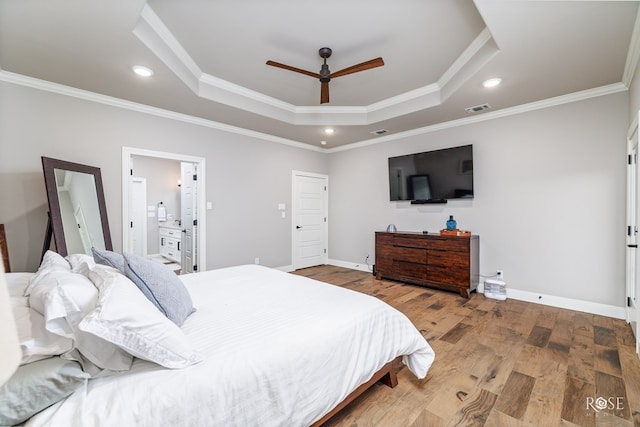 bedroom with ceiling fan, hardwood / wood-style floors, connected bathroom, ornamental molding, and a raised ceiling