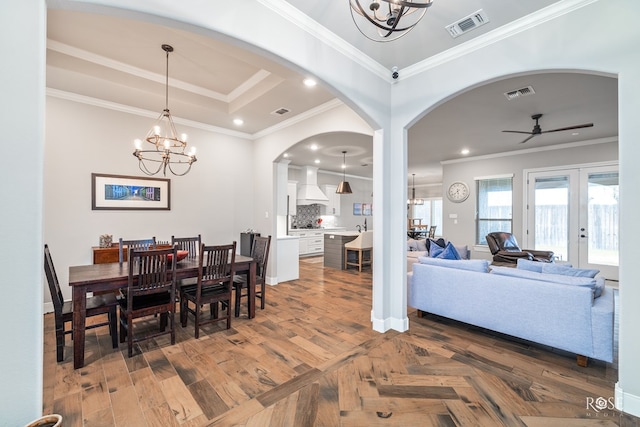 dining room featuring a raised ceiling, crown molding, ceiling fan with notable chandelier, and french doors