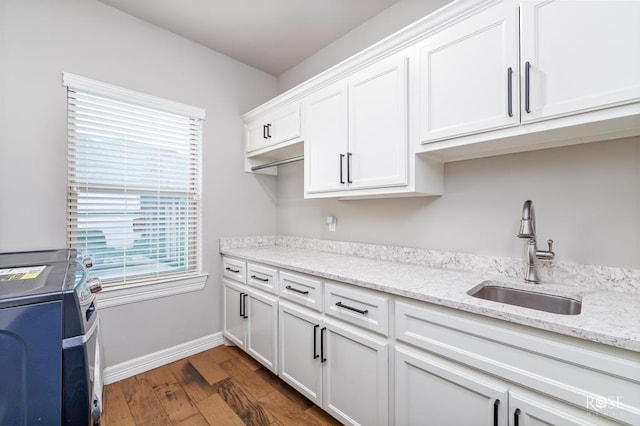 kitchen with light stone countertops, sink, dark wood-type flooring, and white cabinets