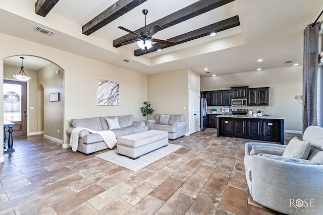 living area with baseboards, visible vents, arched walkways, a ceiling fan, and beam ceiling