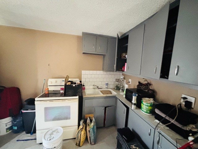 kitchen featuring sink, backsplash, gray cabinetry, white electric range, and a textured ceiling