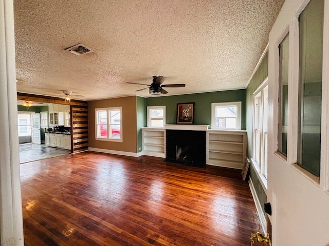 unfurnished living room with ceiling fan, a textured ceiling, and dark hardwood / wood-style flooring