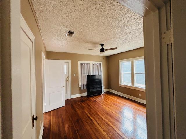 interior space featuring ceiling fan, dark wood-type flooring, and a textured ceiling