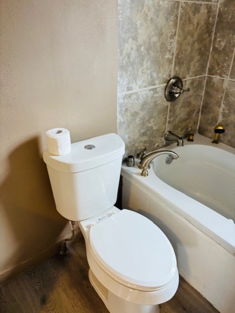 bathroom with toilet, wood-type flooring, and a tub