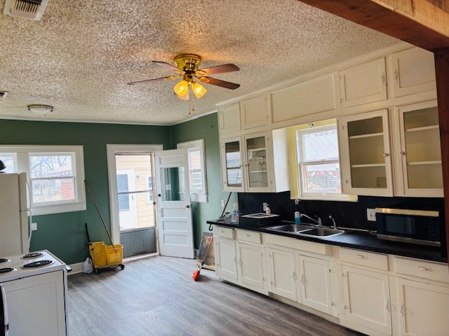 kitchen featuring sink, white appliances, wood-type flooring, and white cabinets