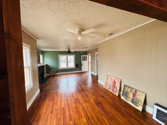 unfurnished living room featuring a textured ceiling, a tile fireplace, ceiling fan, crown molding, and hardwood / wood-style flooring