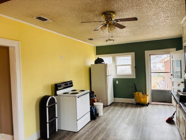 kitchen with a textured ceiling, white appliances, crown molding, and wood-type flooring