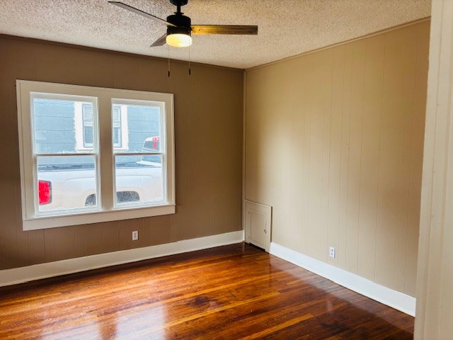 spare room with a textured ceiling, dark wood-type flooring, and ceiling fan